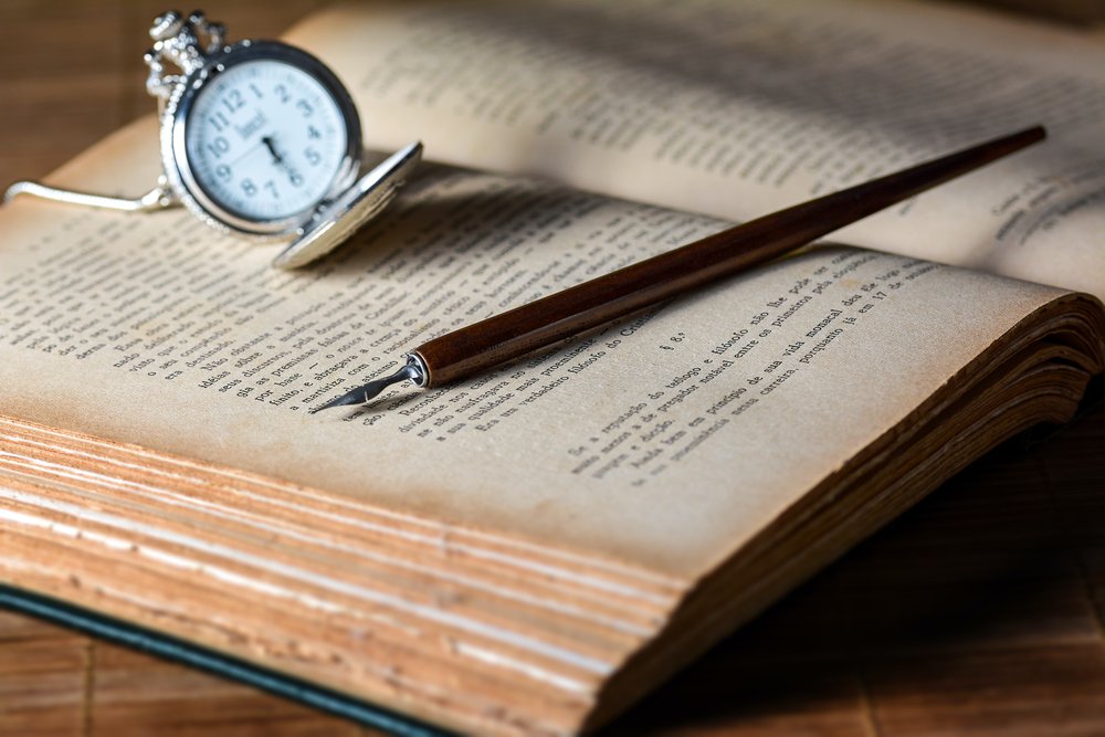 Picture of a open book with a pen and watch on top of it