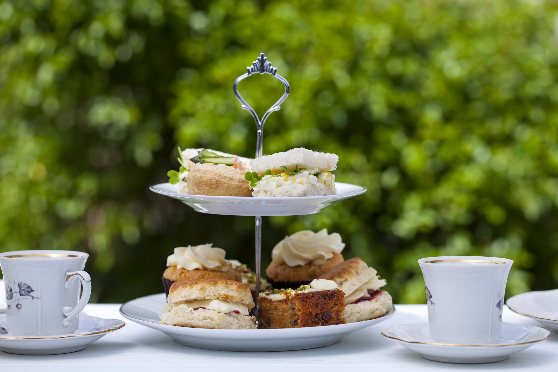 Picture of an afternoon tea table with tea cups and food on a 2 tier plate