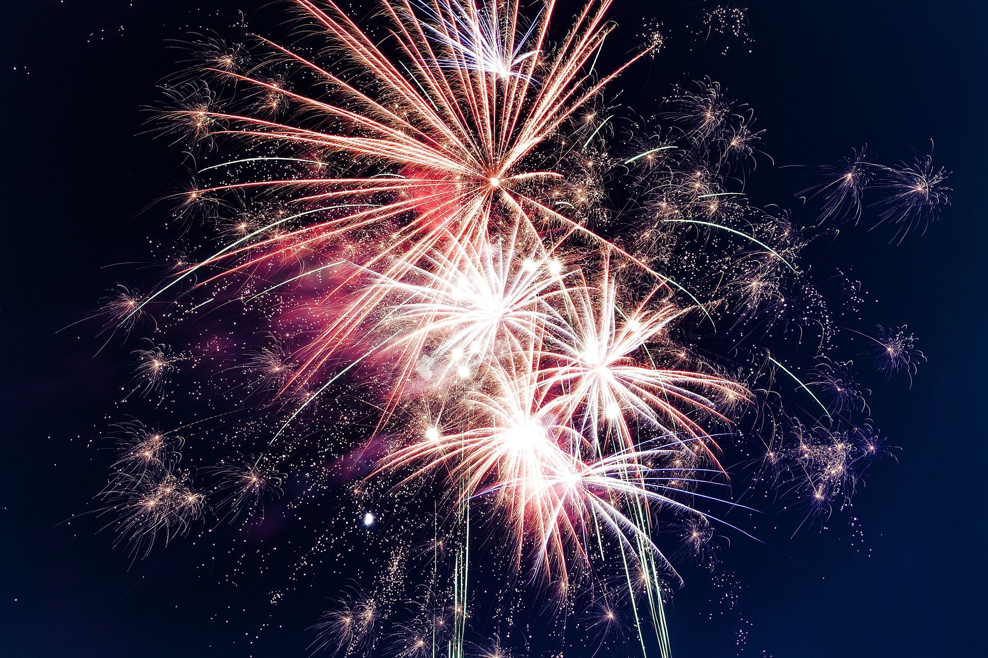 Picture of red and white fireworks exploring on the night sky