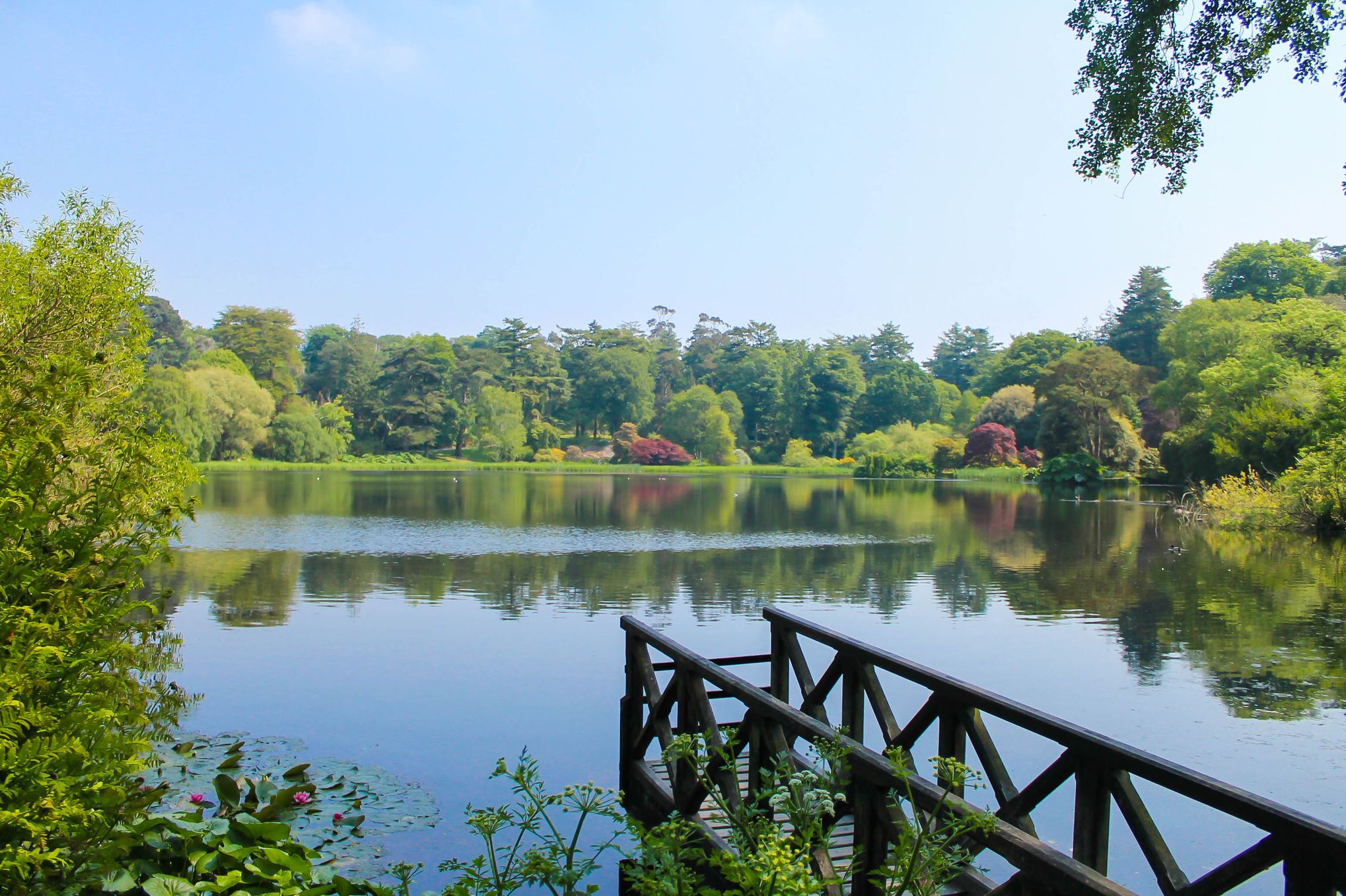 Image of the lake with a wooden pond in the foreground and trees around the lake in the background