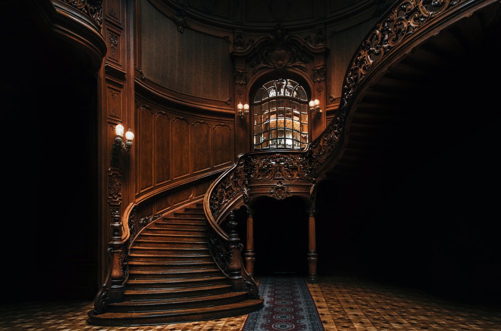 Image from the hall with a sculpted wood stair and lights on the sides