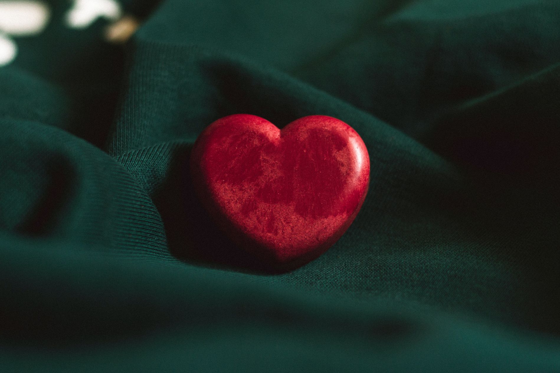 Picture of a wooden heart painted red on top of dark-green cloth